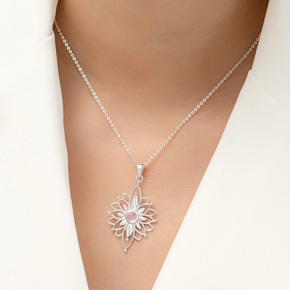 Silver necklace with a floral pendant on a mannequin.