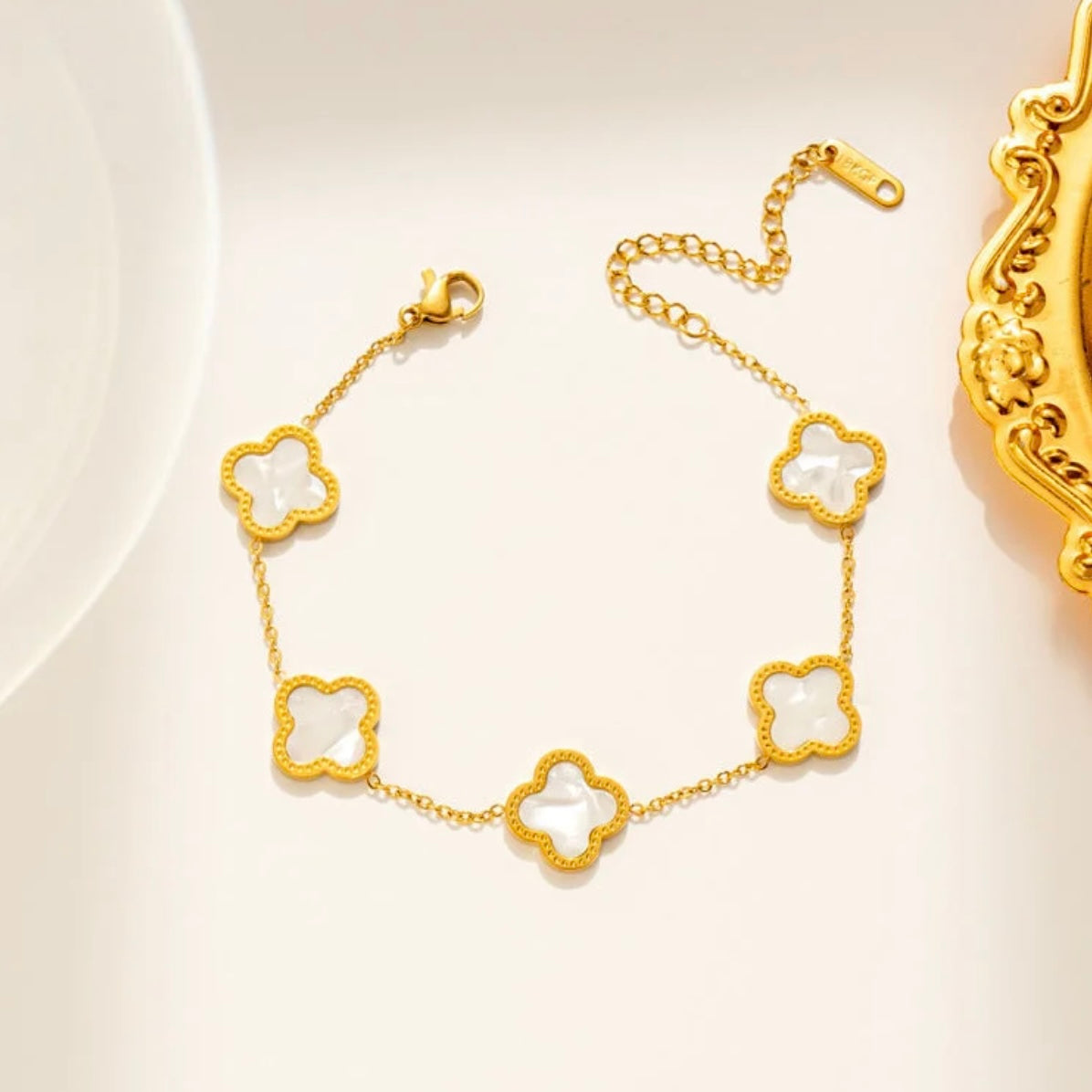 Gold bracelet with clover-shaped links on a light background