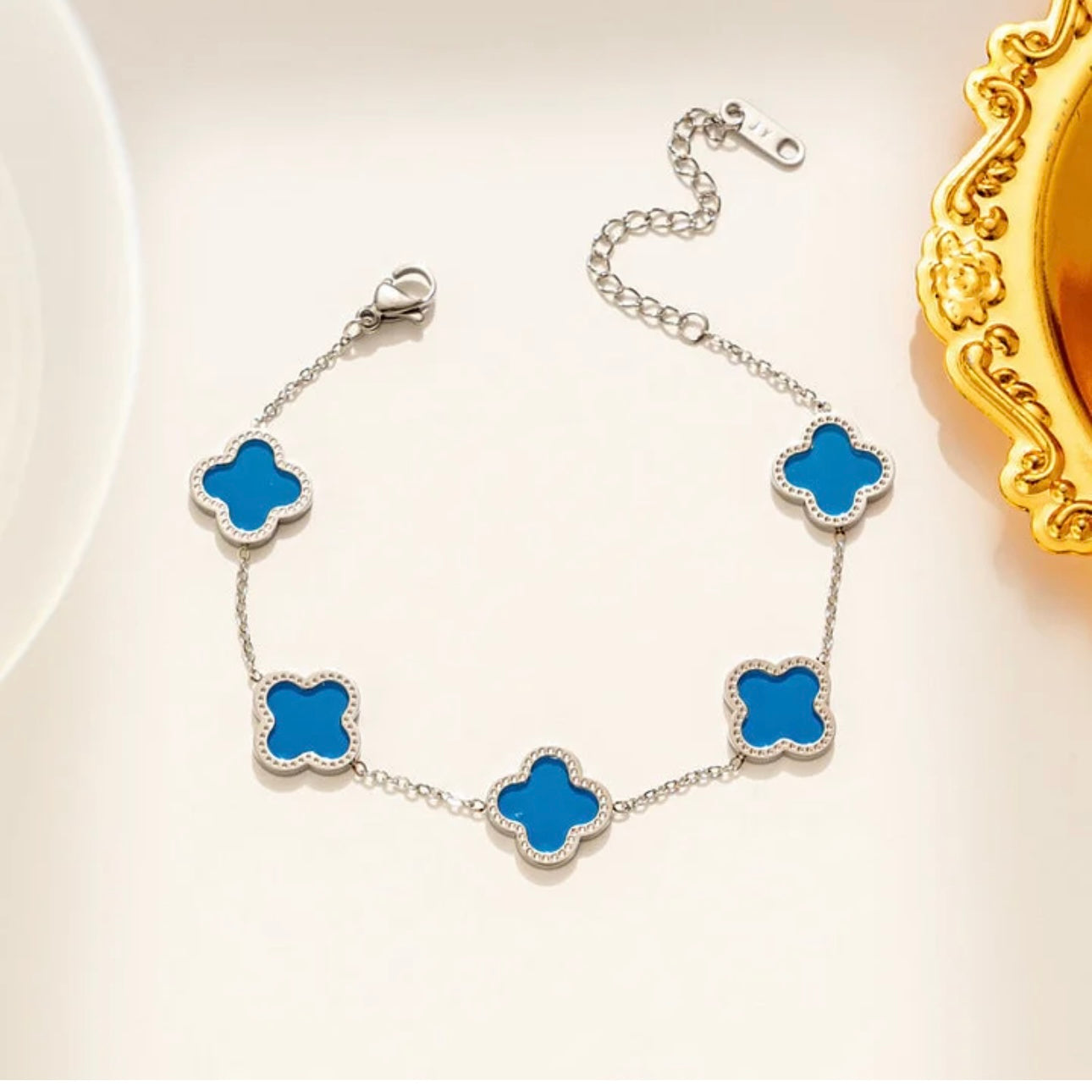 Silver bracelet with blue clover-shaped charms on a light background