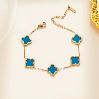 Gold bracelet with blue clover-shaped charms on a light background