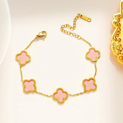 Gold bracelet with pink clover-shaped charms on a light background